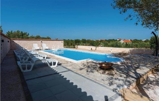 Ummauerte Poolterrasse mit Liegen und Feuerstelle an einem dalmatinischen Ferienhaus in Velika Cista